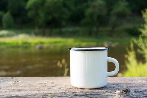 White campfire enamel coffee mug mockup river view.  Empty mug mock up for design promotion.