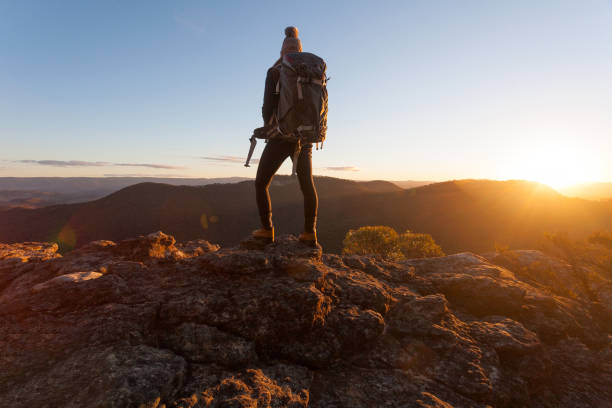 Hiker standing on cliff ledges mountain top Nothing can substitute experience.  Standing on the edge of Mt Victoria  as the golden sun dips low on the horizon blue mountains australia photos stock pictures, royalty-free photos & images