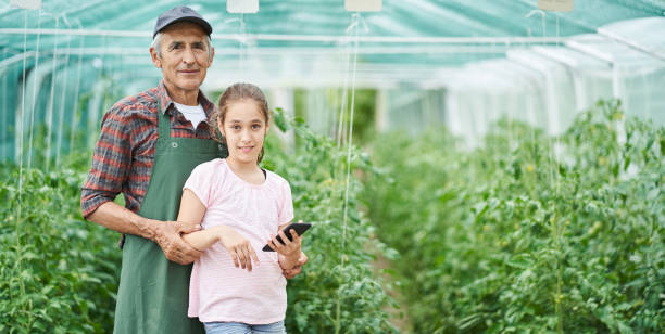 little girl and senior farmer in greenhouse - casual granddaughter farmer expressing positivity imagens e fotografias de stock