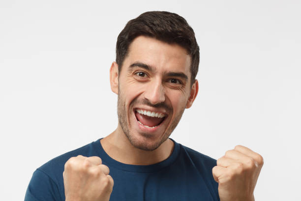 istock Young attractive male shouting while his team win, raised both fist in victory gesture, isolated on gray background 997461974