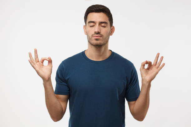 istock Concentrated relaxed man in blue t-shirt with closed eyes, having relaxation while meditating, trying to find balance and harmony. Yoga and meditation concept 997462114