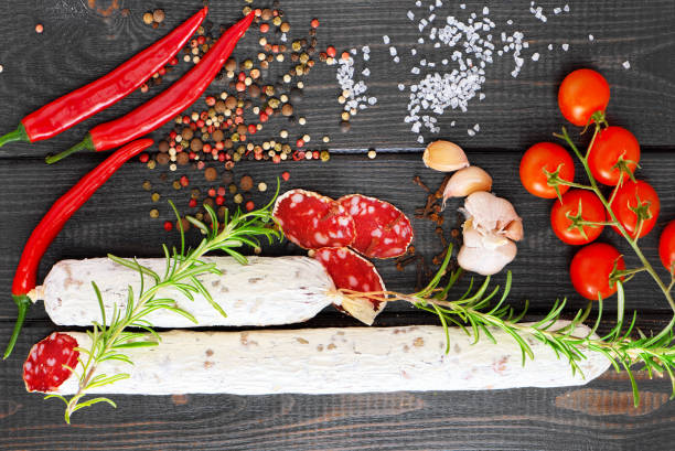 istock Sliced cured sausage with spices, chili pepper on a black background. 997473430