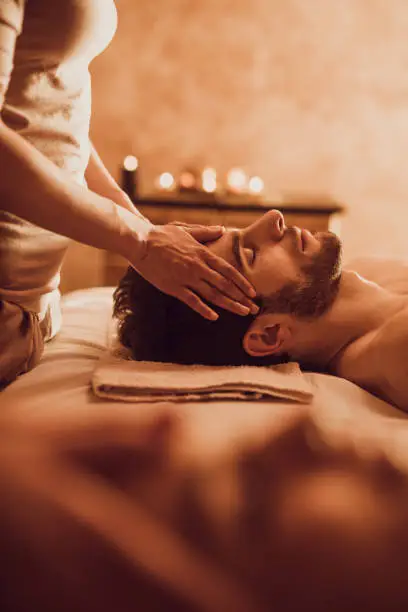 Young man getting head massage by unrecognizable therapist at the spa.