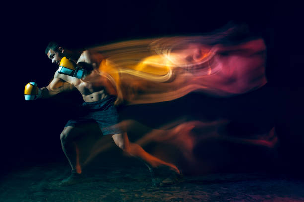 istock Male boxer boxing in a dark studio 997504256