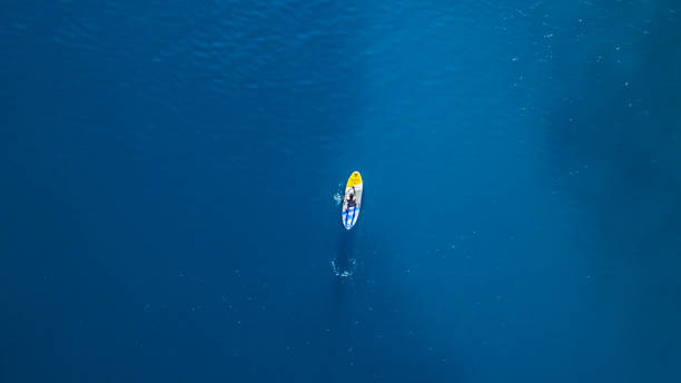 widok z lotu ptaka młodego człowieka jeżdżącego na paddleboardzie - paddling zdjęcia i obrazy z banku zdjęć