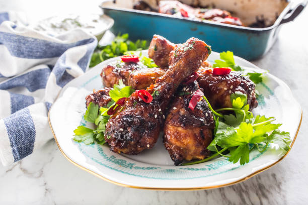 Grilled roasted and barbecue chicken legs on white plate with herb decoration.