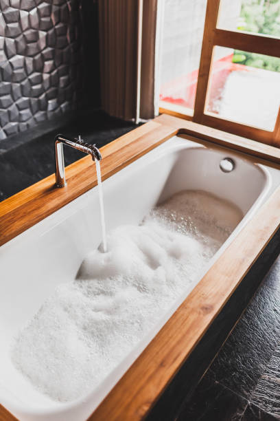 водяная ванна с пеной. современный стиль ванной комнаты с деревянным краем и черными стенами - full steam ahead стоковые фото и изображения