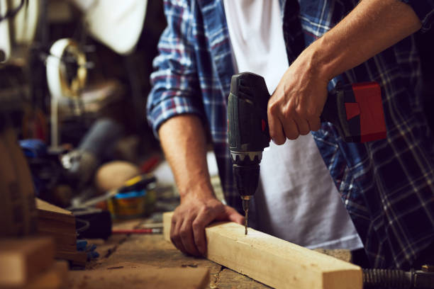 istock Carpenter working with an electric drill into a wooden board 997523990