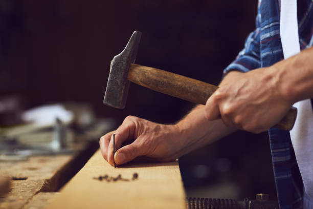 istock Carpenter hammering a nail into wooden plank 997523994