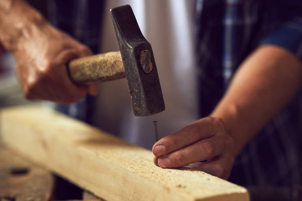 istock Close up carpenter hammering a nail into wooden plank 997524000