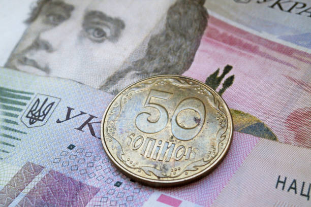 Ukrainian hryvnia coin and banknotes as background.