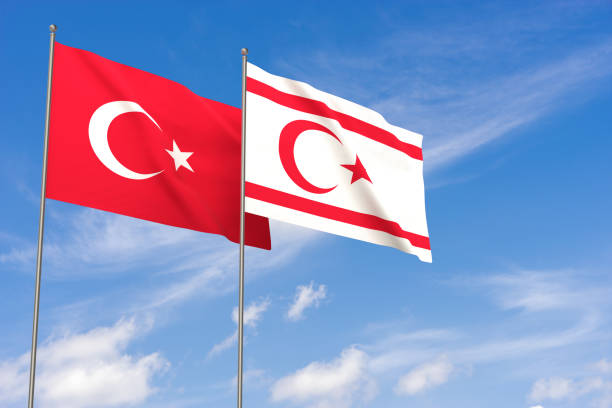 Turkey and Turkish Republic of Northern Cyprus flags over blue sky background. stock photo