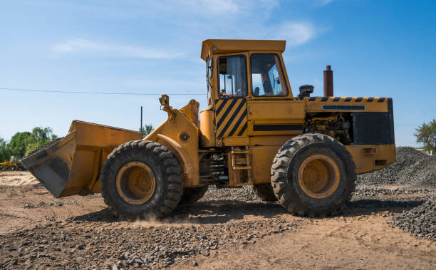 istock Yellow loader moving with uploaded bucket with stone gravel during road construction works. The stones for the road. Unloading stone. 997536714