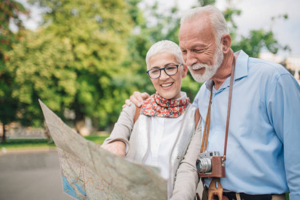 istock Elderly man with camera hugging his wife looking at touristic map 997548870