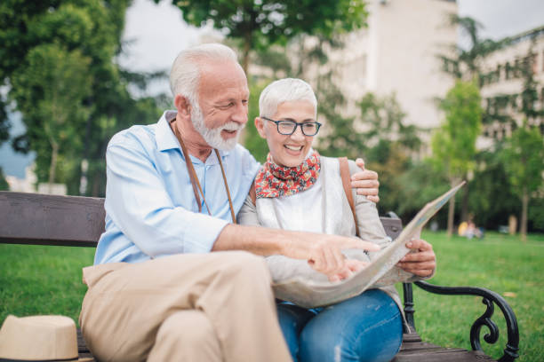 istock Mature couple reading the map while sitting on park bench 997548974