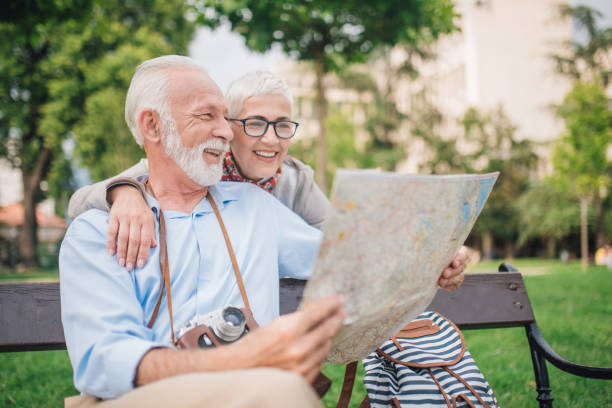 istock Married senior couple hugging and looking at the map 997549016