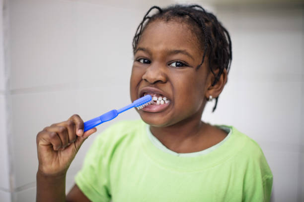 istock Cute girl brushing teeth in kindergarten bathroom 997554310