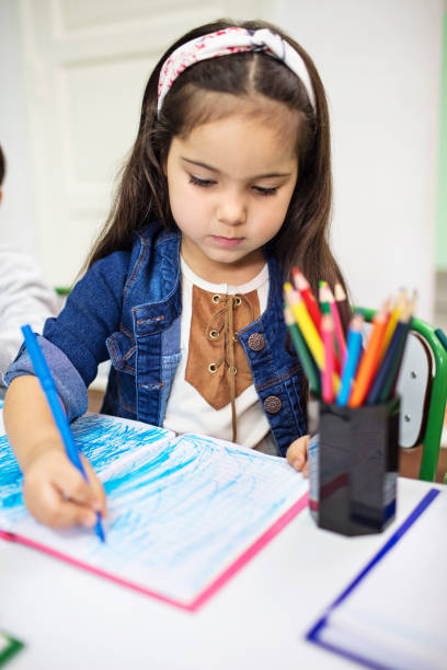 istock Little girl drawing with colored pencil in book 997559564