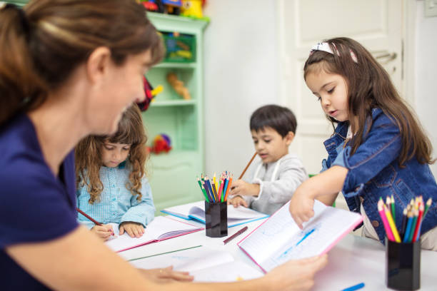 istock Teacher and students in playschool drawing class 997562578
