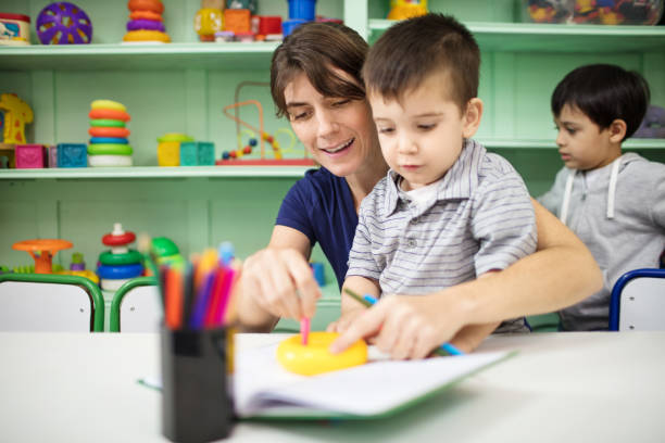 insegnante che assiste il bambino nel disegno del libro - circle child preschool preschooler foto e immagini stock