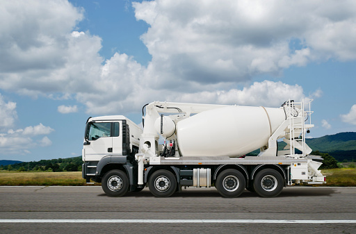 Side view of an white cement mixer on the road.