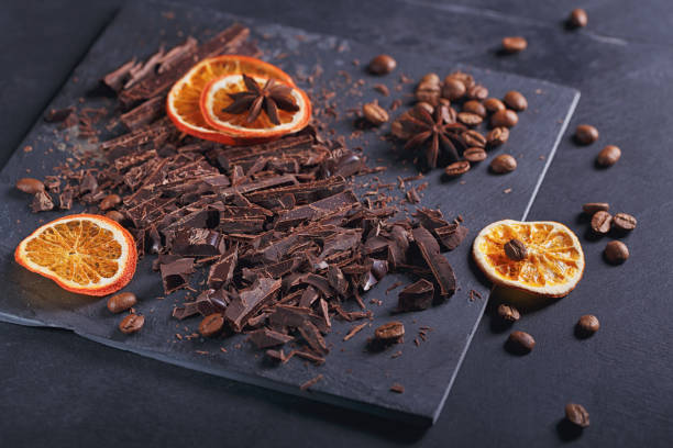 istock Dark chopping chocolate, black roasted coffee beans, dried lemon slices on dark background 997575212