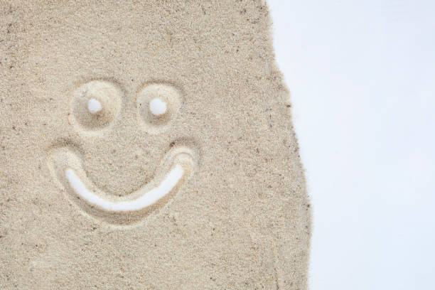 Smily face drawn on sand in white isolated background.