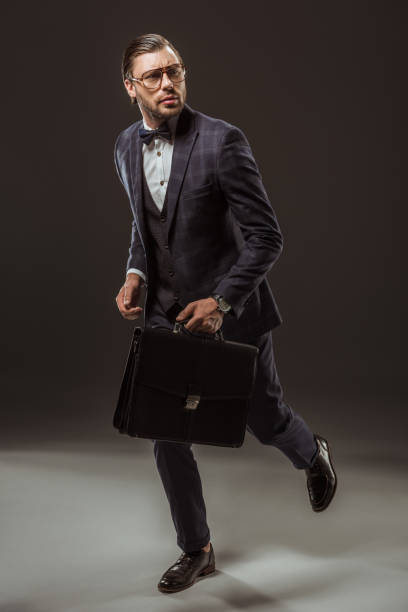 istock serious businessman with briefcase running and looking away on black 997592690