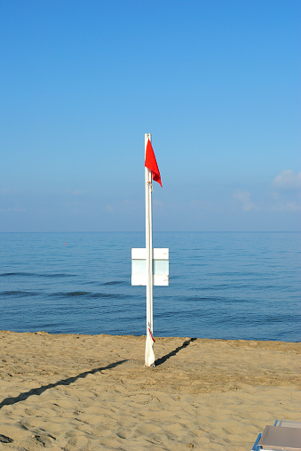 red flag on the beach means danger and rough seas, no swimming, vertical background