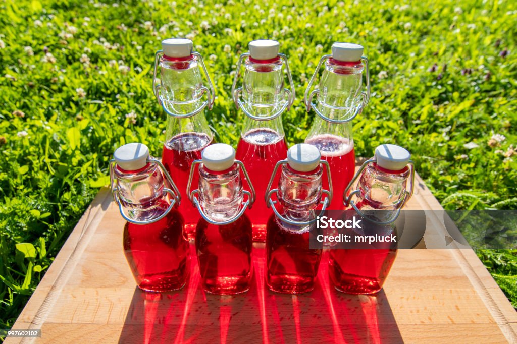 glass bottles of homemade cherry juice glass bottles of homemade cherry juice in the summer sun Austria Stock Photo