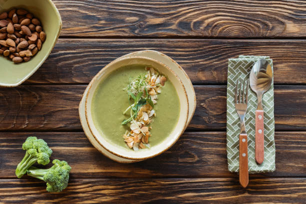 vista dall'alto della zuppa di crema vegetariana organizzata, posate e ingredienti su superficie in legno - cream of broccoli foto e immagini stock