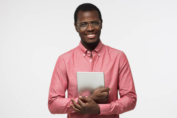 istock Horizontal studio portrait of positive African American guy pictured isolated on white background wearing casual clothes and holding tablet getting ready for presentation or enjoying leisure time 997616608