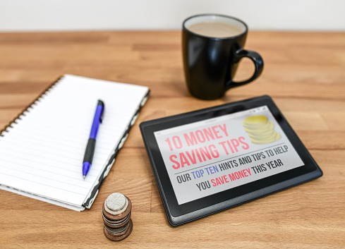 Concept of a Tablet device with money saving tips and a notepad and mug
+ screen mocked up by author