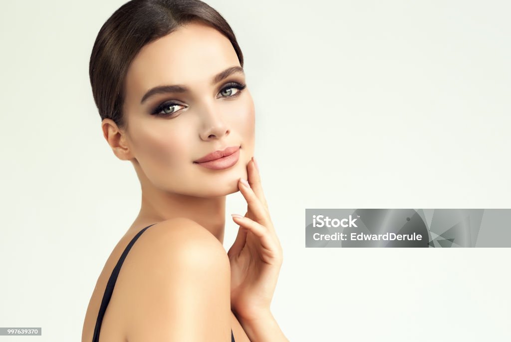 Beauty-style portrait of appealing, young woman. Makeup and beauty technologies. Beauty-style portrait of appealing, young woman. Smokey-eyes style bright makeup and hair gathered in a tuft, tender look on viewer. Makeup, cosmetology and beauty technologies. Women Stock Photo