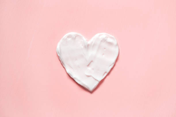 istock Heart shape from cream in pink background. Skin care 997647086