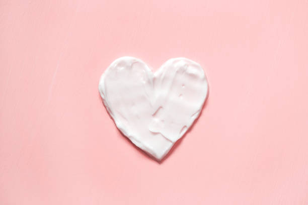 Heart shape from cream in pink background. Skin care stock photo