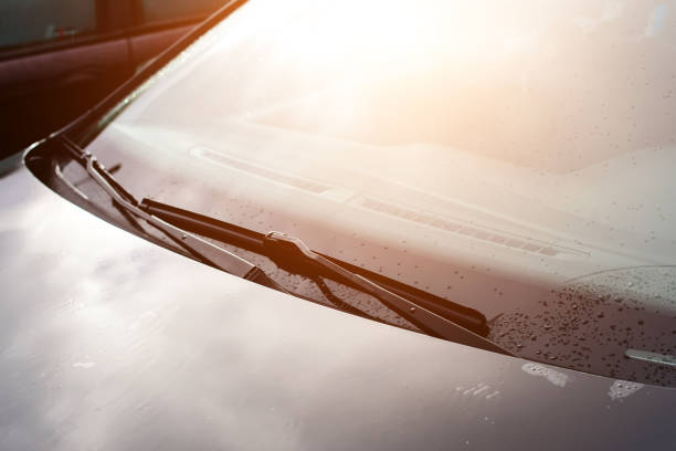 istock Windshield wipers of a gray car with drops after raining in rays 997655192