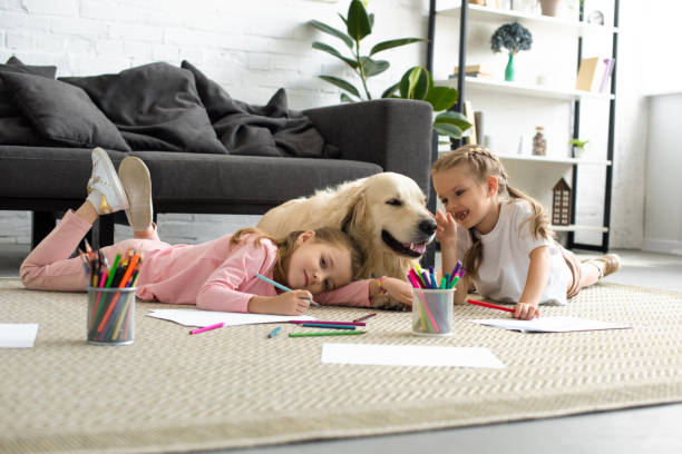 bambini sorridenti sdraiati sul pavimento insieme al cane golden retriever a casa - golden retriever friendship white small foto e immagini stock