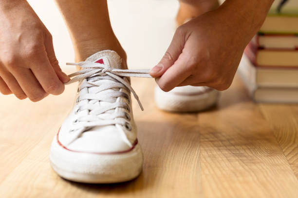 istock White sneakers and stack of books on the floor. Student, education and knowledge concept 997659992