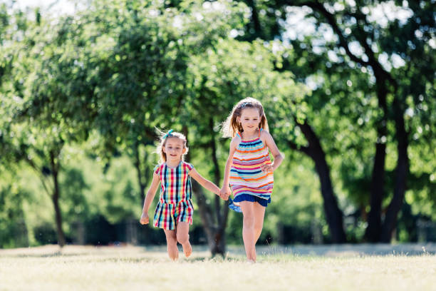 istock Two little smiling girls running on the grass, holding hands 997673022