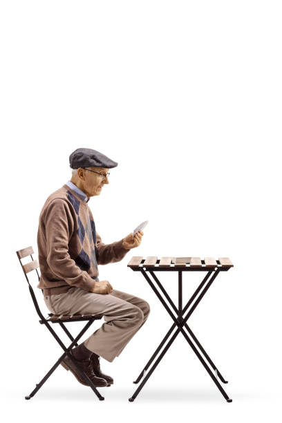 istock Senior seated at a table playing cards 997678486