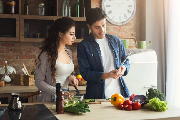 istock Beautiful young couple reading recipe on tablet 997686356