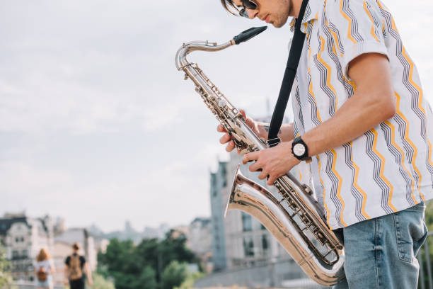 istock Young hipster man with saxophone performing on street 997693122