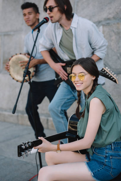istock Multiracial young people with guitars and djembe performing on street 997699594