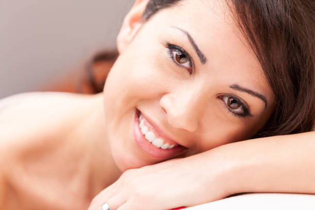 istock beautiful coy woman smiling on her sofa 997705328