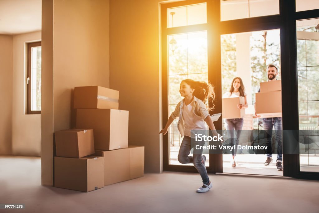 Family moving in new house Happy family with cardboard boxes in new house at moving day. Moving House Stock Photo
