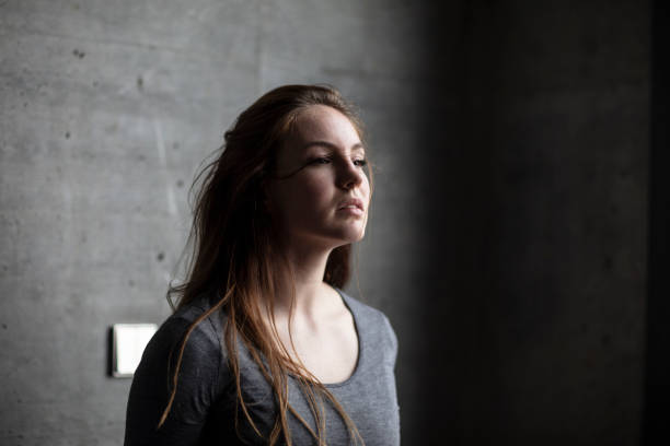 istock Angled View of Female Model Behind Grey Concrete Wall 997720486