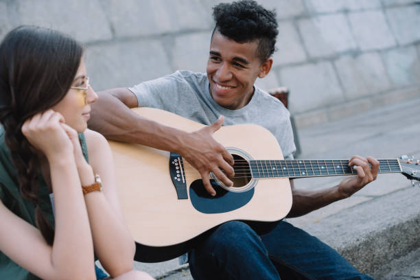 istock Multiracial young people playing guitar and singing on street 997724430