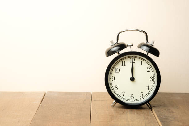 istock black vintage alarm clock close to the window present twelve o'clock, midday or midnight 997725040