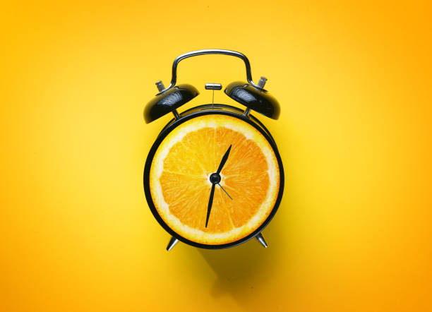 istock Alarm Clock of Orange Fruit on Yellow Background 997725582